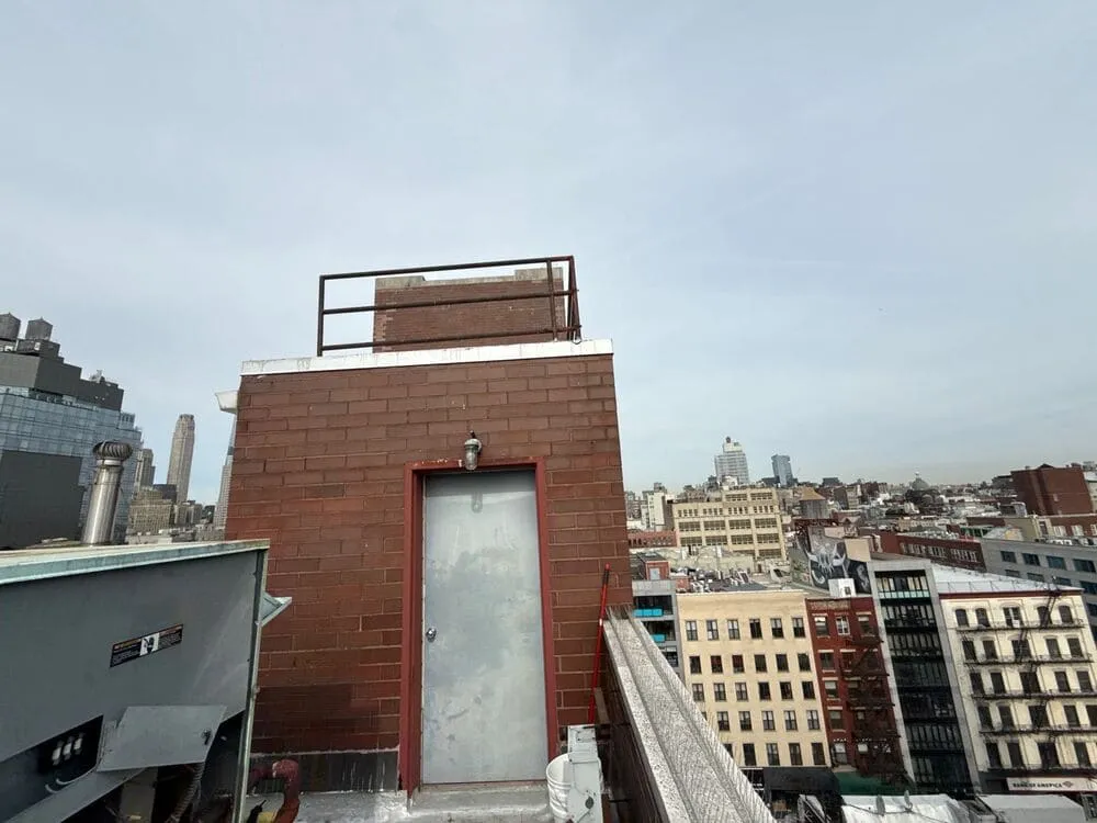 Rooftop utility access with backdrop of NYC skyline, illustrating the gritty challenges local windows face daily.