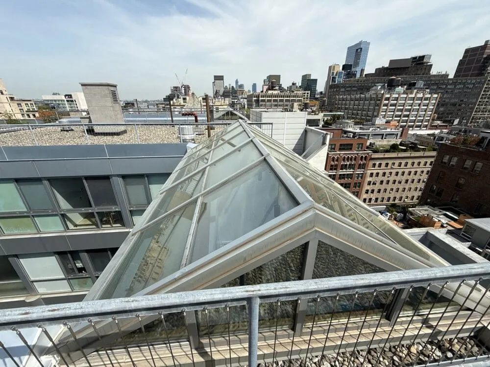 Rooftop glass atrium catching sunlight, representing how clear panes boost daylight flow and creative energy indoors.